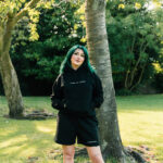 Girl wearing 'work in progress' hoodie in black.